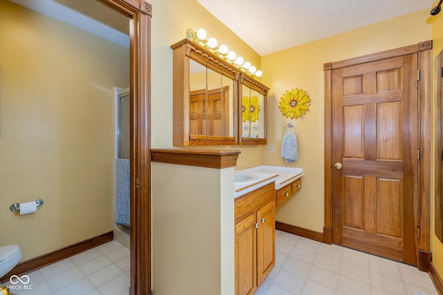 bathroom featuring vanity, a textured ceiling, toilet, and walk in shower