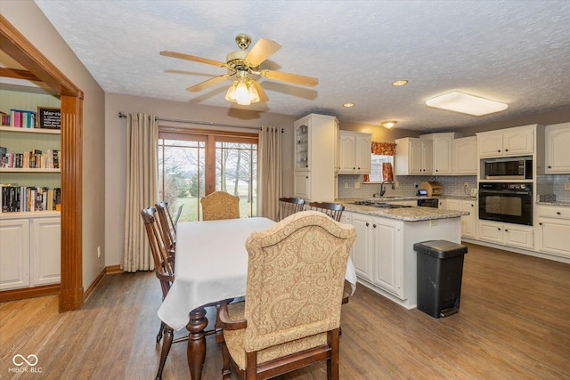 dining room featuring ceiling fan, a textured ceiling, and light wood-type flooring