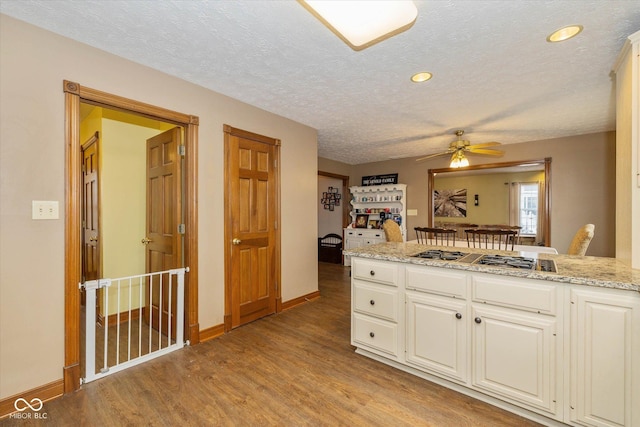 kitchen featuring light hardwood / wood-style floors, stainless steel gas cooktop, a textured ceiling, and white cabinets