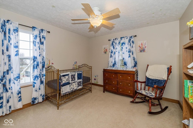 carpeted bedroom with ceiling fan and a textured ceiling