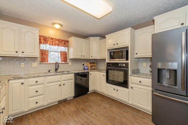 kitchen with dark wood-type flooring, sink, light stone countertops, decorative backsplash, and black appliances