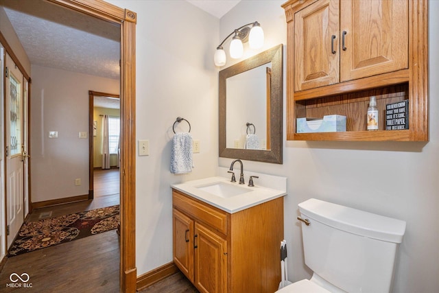 bathroom with vanity, wood-type flooring, toilet, and a textured ceiling