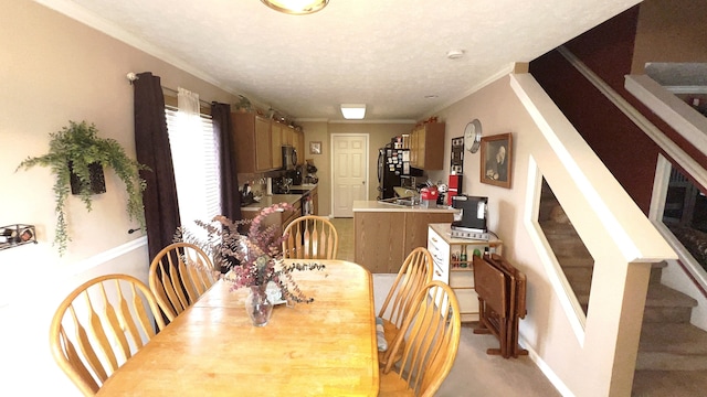 dining space featuring sink, light colored carpet, ornamental molding, and a textured ceiling