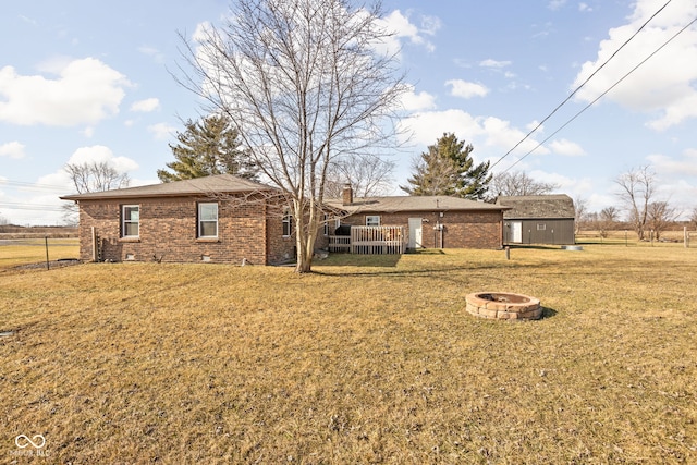 back of house with an outbuilding, an outdoor fire pit, and a lawn