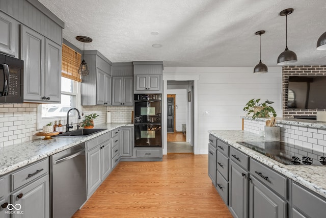 kitchen with gray cabinets, sink, hanging light fixtures, and black appliances