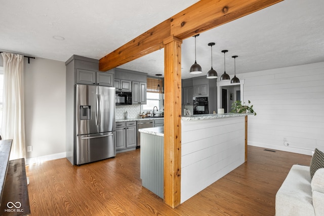 kitchen with gray cabinetry, beamed ceiling, wood-type flooring, and black appliances