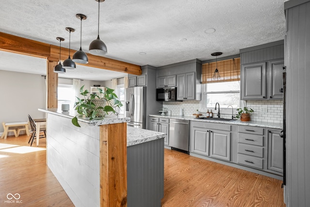 kitchen featuring sink, light stone counters, gray cabinets, stainless steel appliances, and light hardwood / wood-style floors