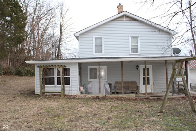 rear view of property featuring covered porch and a lawn