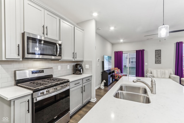 kitchen featuring decorative light fixtures, sink, backsplash, stainless steel appliances, and light stone countertops