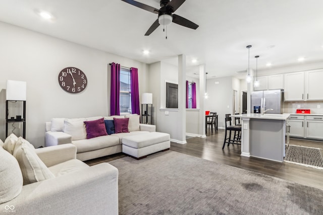 living room with dark wood-type flooring, sink, and ceiling fan