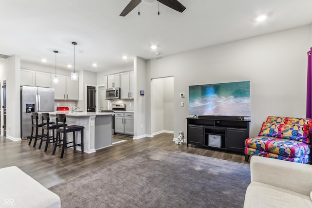 living room with ceiling fan and dark hardwood / wood-style floors