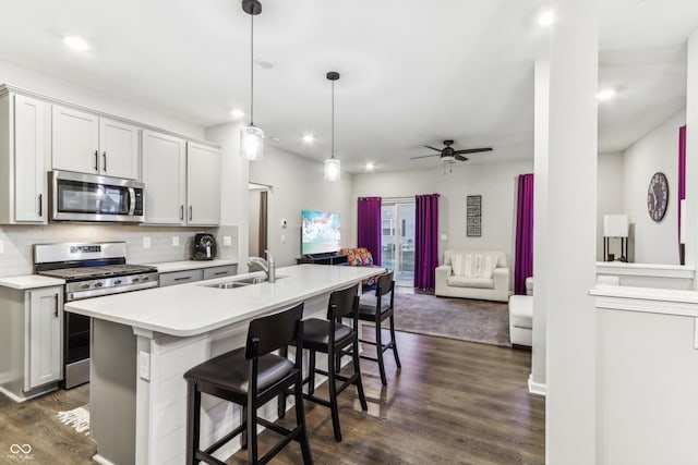 kitchen featuring a breakfast bar, sink, decorative light fixtures, a center island with sink, and stainless steel appliances