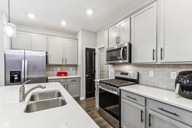 kitchen featuring light stone counters, stainless steel appliances, sink, and hanging light fixtures