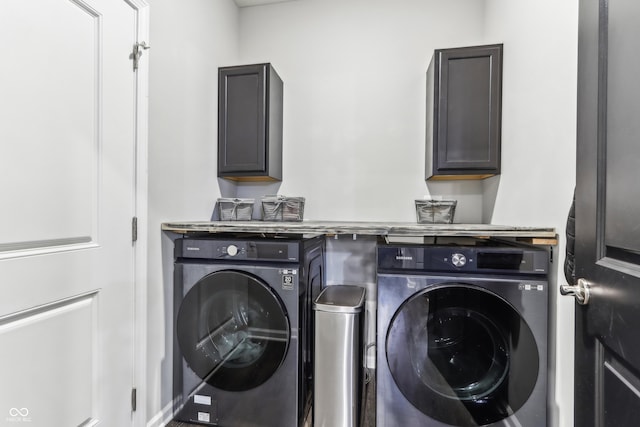 clothes washing area featuring cabinets and washing machine and dryer