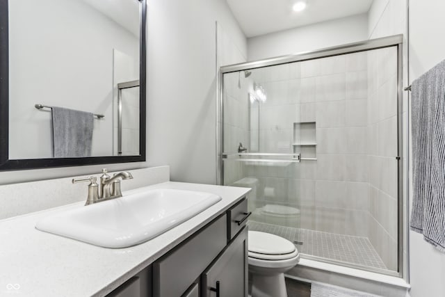 bathroom with a shower with door, vanity, and toilet