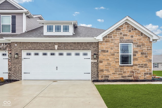 view of front facade featuring stone siding, a garage, driveway, and roof with shingles