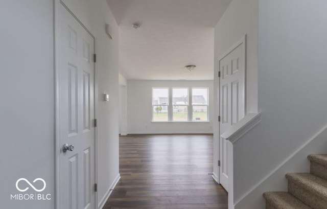 hallway with dark wood-type flooring, stairway, and baseboards