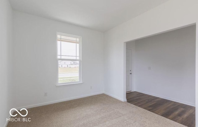 empty room featuring a healthy amount of sunlight, baseboards, and dark carpet