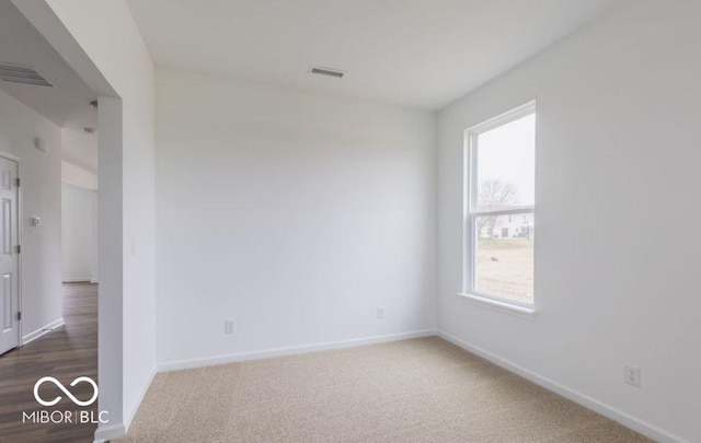 spare room with visible vents, dark carpet, and baseboards