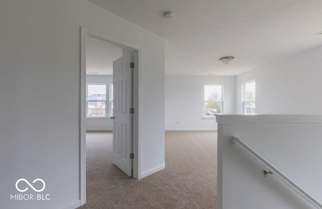 corridor with carpet floors, baseboards, and an upstairs landing