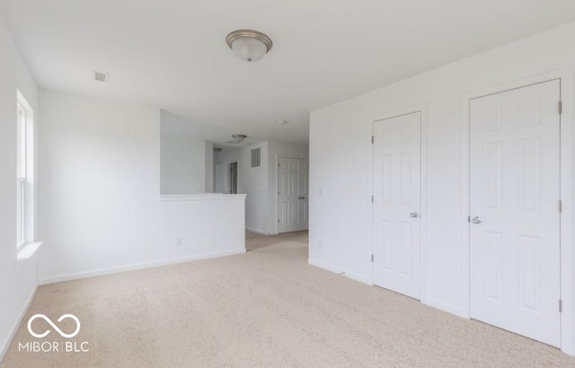 spare room with light carpet and baseboards