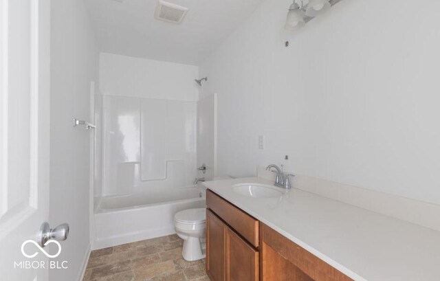 bathroom featuring visible vents, toilet, stone finish flooring, tub / shower combination, and vanity