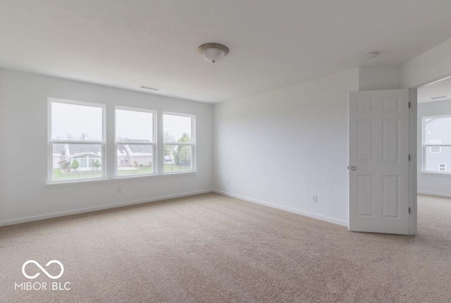 empty room featuring light carpet and baseboards