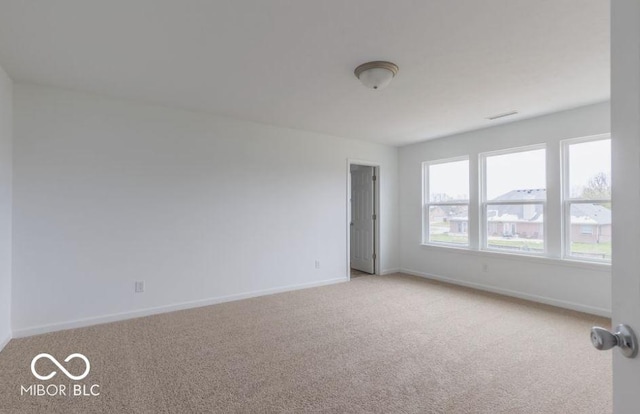 empty room with visible vents, baseboards, and light colored carpet