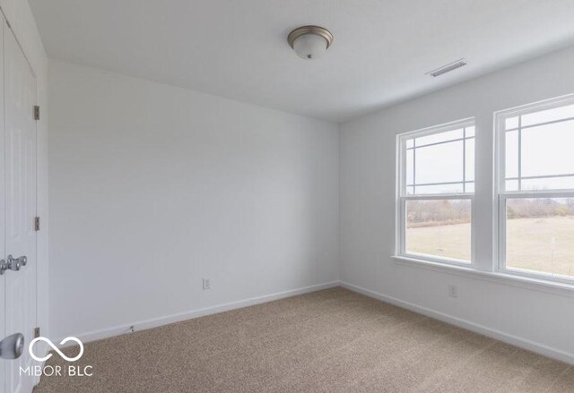 carpeted spare room with baseboards and visible vents