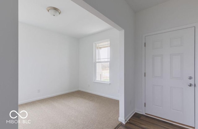 entryway featuring baseboards and dark colored carpet