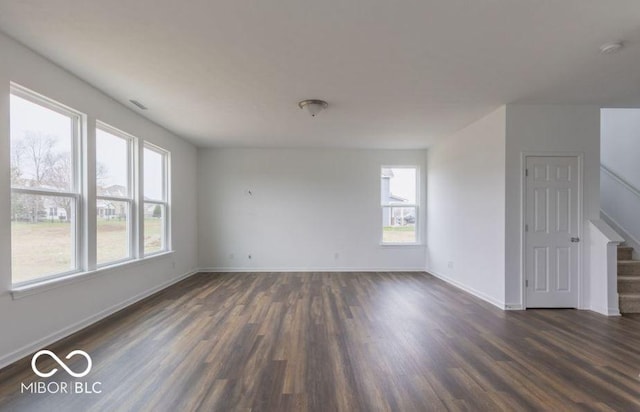 unfurnished room featuring stairs, baseboards, and dark wood finished floors