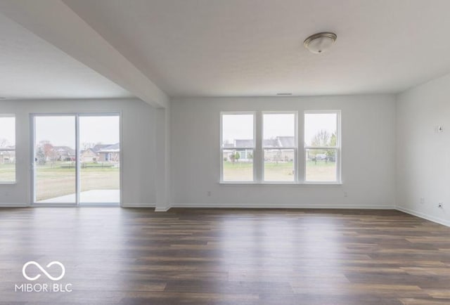 unfurnished room with dark wood-style flooring and baseboards