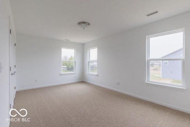 spare room featuring light carpet, visible vents, and baseboards