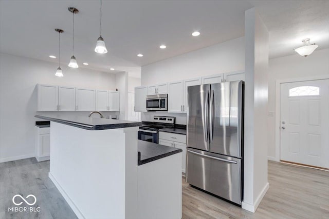 kitchen with white cabinetry, stainless steel appliances, a center island, and hanging light fixtures