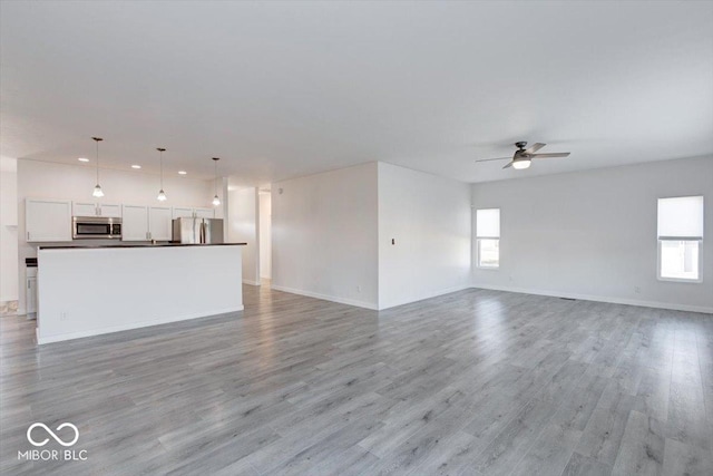 unfurnished living room with ceiling fan and light hardwood / wood-style floors