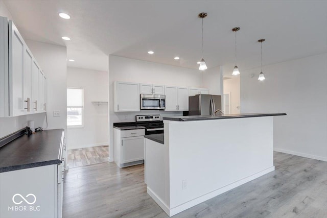 kitchen with pendant lighting, a kitchen island with sink, stainless steel appliances, and white cabinets