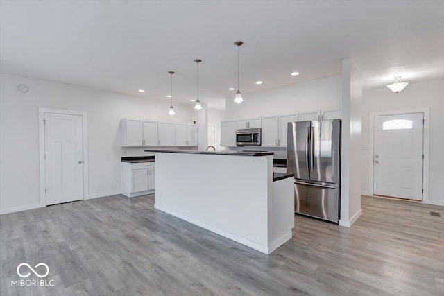 kitchen with white cabinetry, decorative light fixtures, an island with sink, and appliances with stainless steel finishes