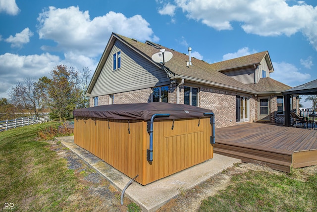 back of property featuring a yard, a deck, a gazebo, and a hot tub