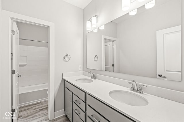 full bathroom with wood finished floors, tub / shower combination, a sink, and double vanity