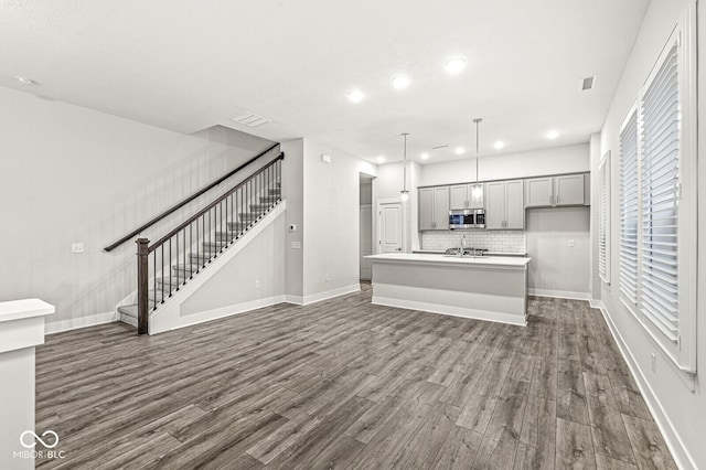 unfurnished living room with baseboards, stairs, visible vents, and dark wood-type flooring