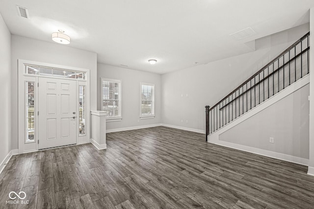 entrance foyer with stairway, dark wood finished floors, visible vents, and baseboards