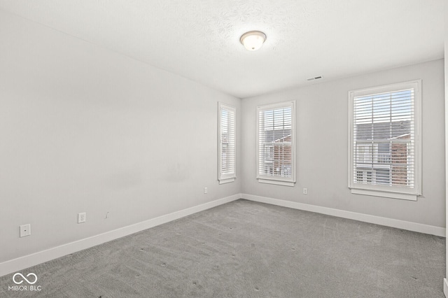 unfurnished room featuring baseboards, a textured ceiling, and carpet flooring