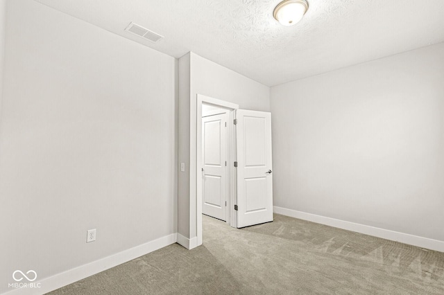 unfurnished bedroom with visible vents, light carpet, baseboards, and a textured ceiling