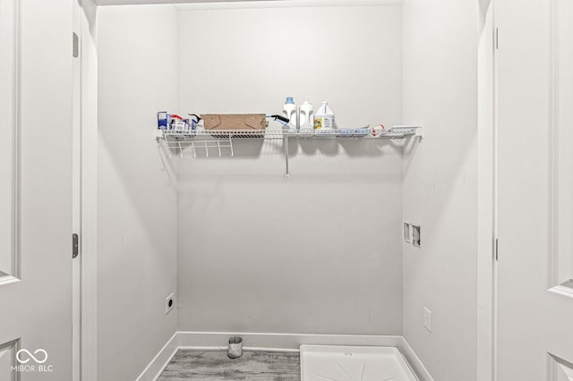 clothes washing area with hookup for a washing machine, laundry area, baseboards, and wood finished floors