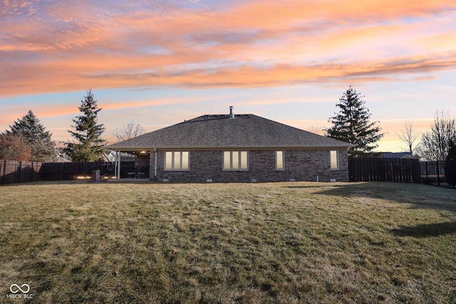 back house at dusk with a lawn