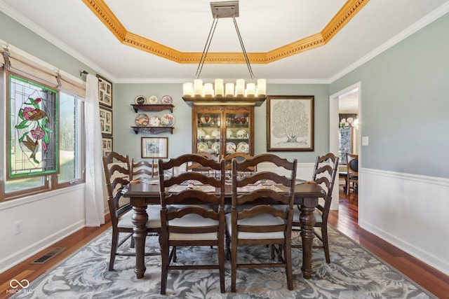 dining room with a raised ceiling, ornamental molding, and dark hardwood / wood-style flooring