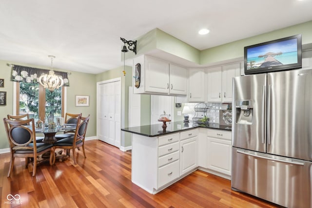 kitchen featuring white cabinetry, decorative light fixtures, kitchen peninsula, and stainless steel fridge with ice dispenser