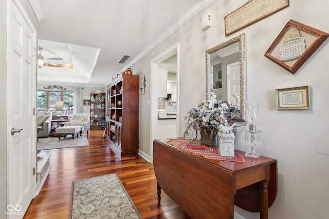 hallway with a raised ceiling, ornamental molding, and dark hardwood / wood-style flooring