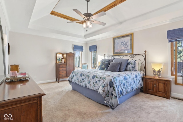 bedroom featuring multiple windows, ornamental molding, a tray ceiling, and light carpet