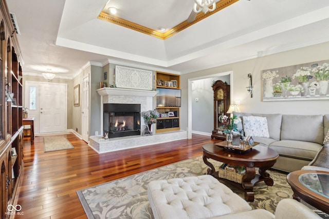 living room with hardwood / wood-style flooring, crown molding, and a raised ceiling